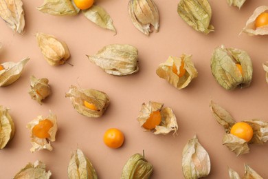 Ripe physalis fruits with calyxes on beige background, flat lay