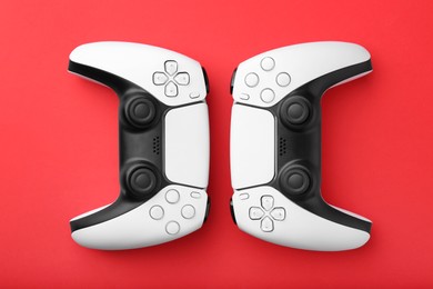 Wireless game controllers on red background, flat lay