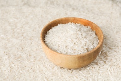 Photo of Raw basmati rice and bowl as background, closeup. Space for text