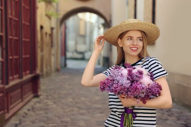 Photo of Beautiful woman with bouquet of spring flowers on city street, space for text