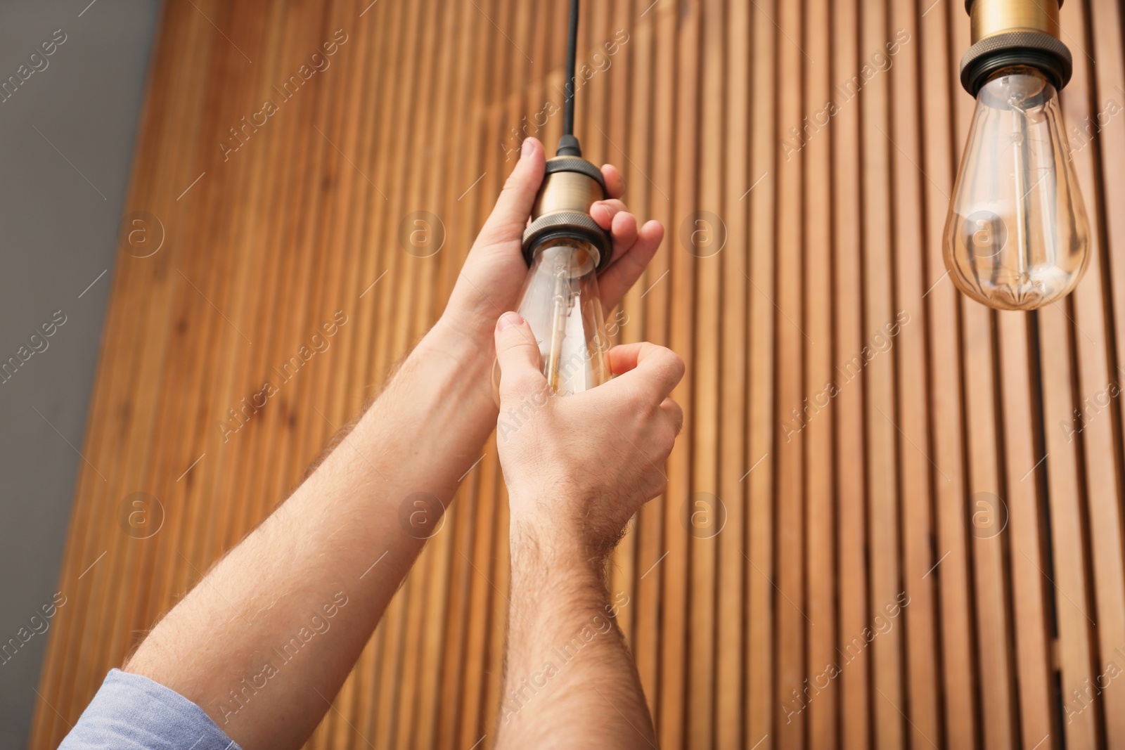 Photo of Man changing lamp light bulb indoors, closeup