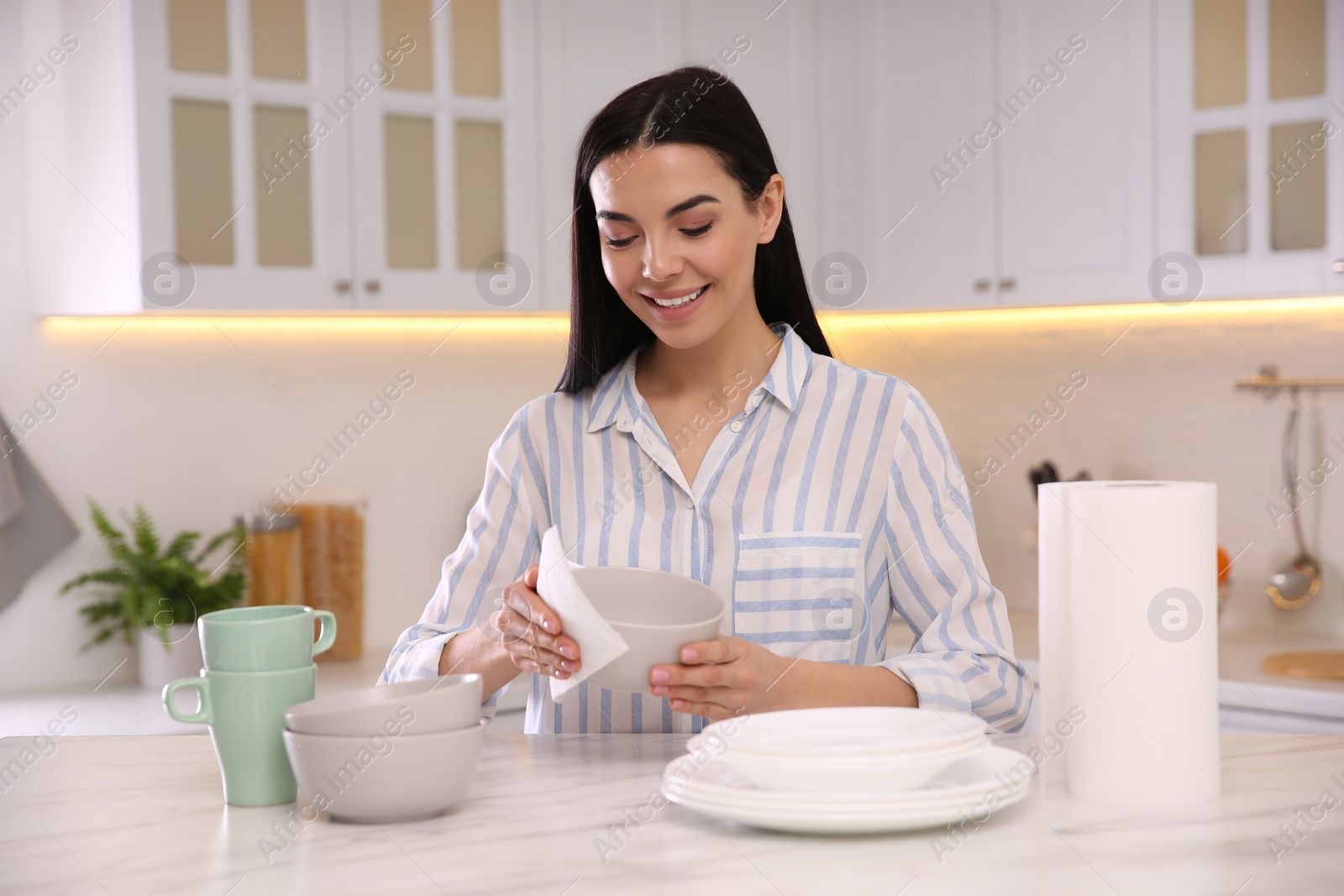 Photo of Woman wiping bowl with paper towel in kitchen