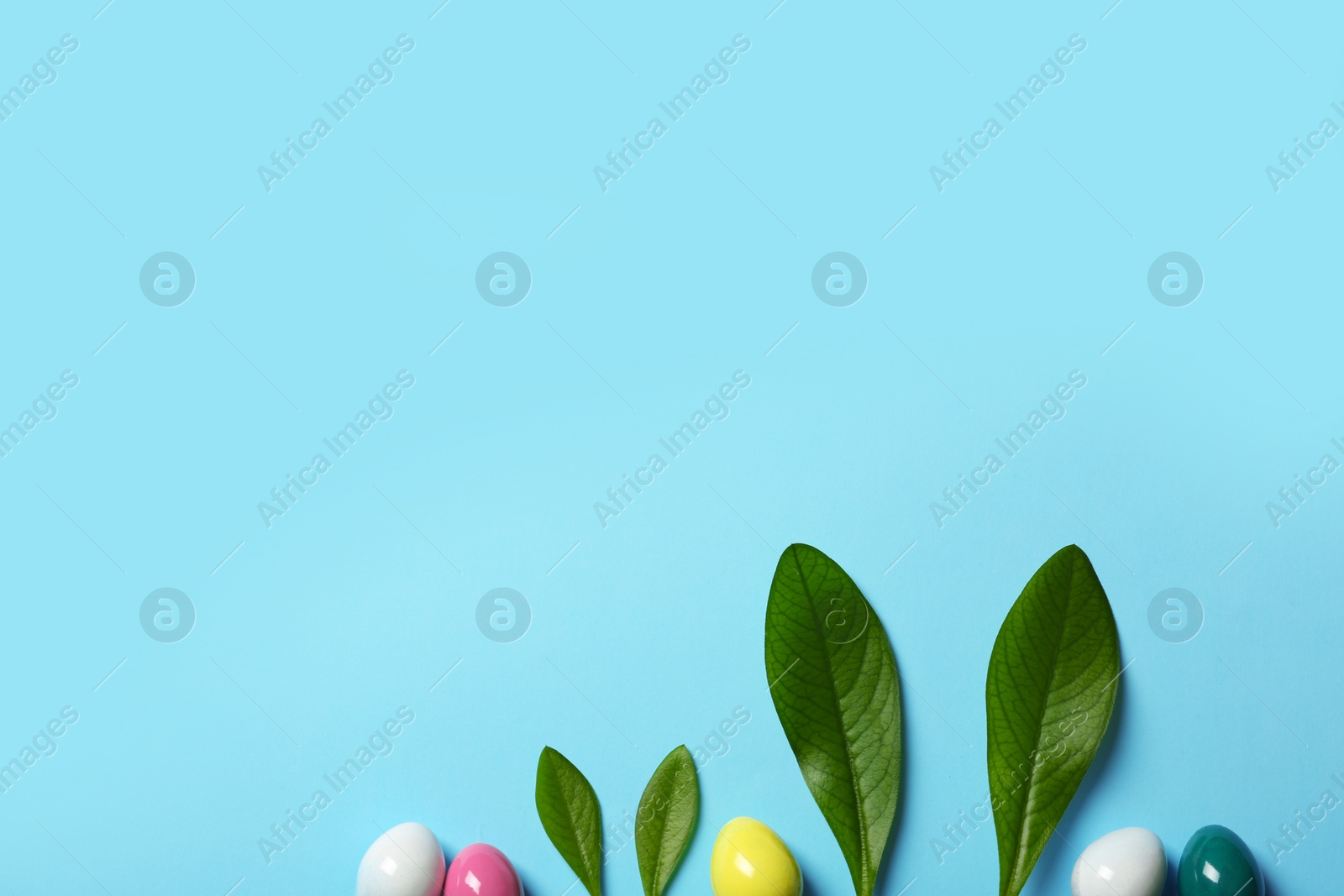 Photo of Creative flat lay composition with Easter bunny ears of green leaves and eggs on color background, space for text