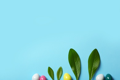 Creative flat lay composition with Easter bunny ears of green leaves and eggs on color background, space for text