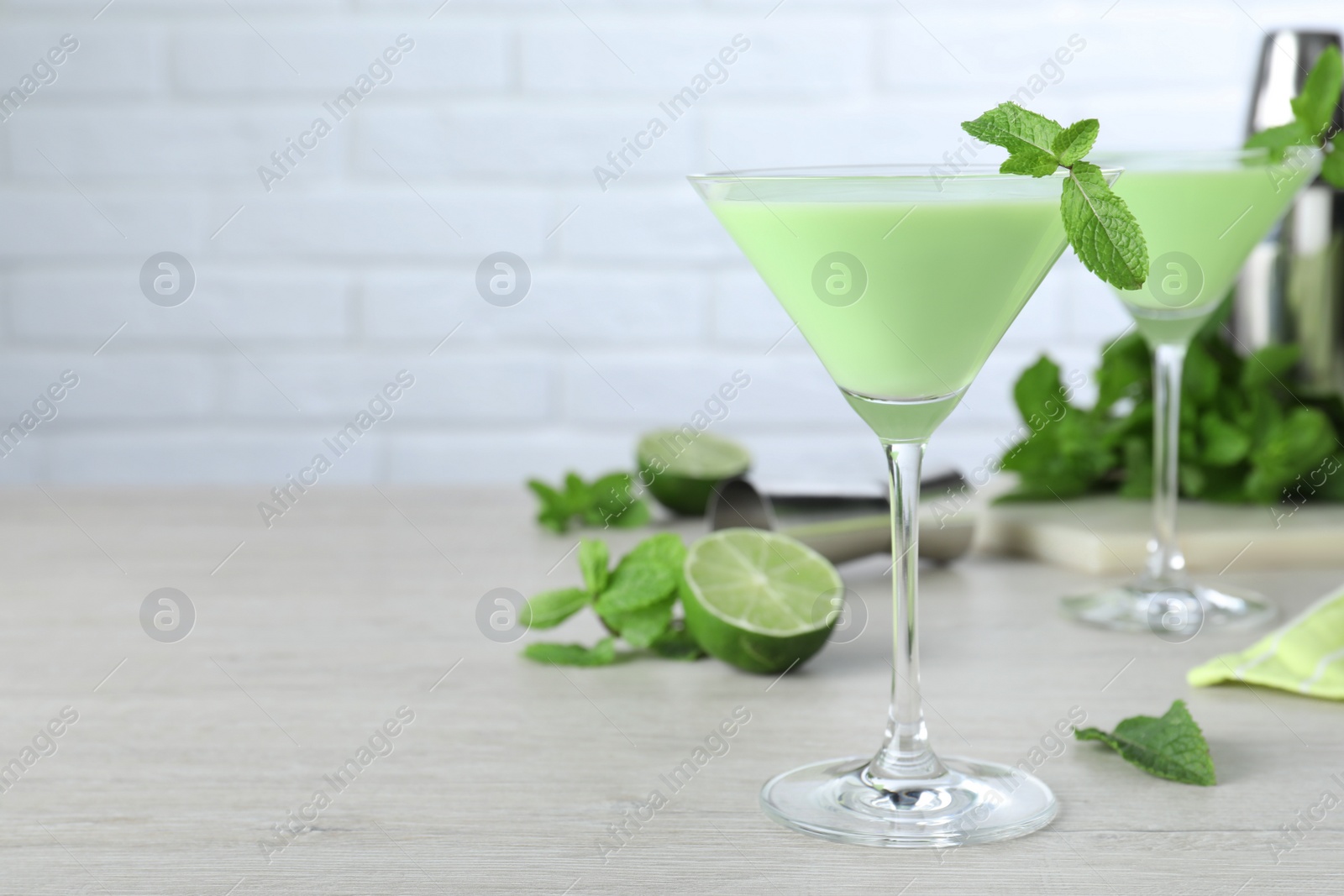 Photo of Delicious mint liqueur with green leaves on white wooden table. Space for text