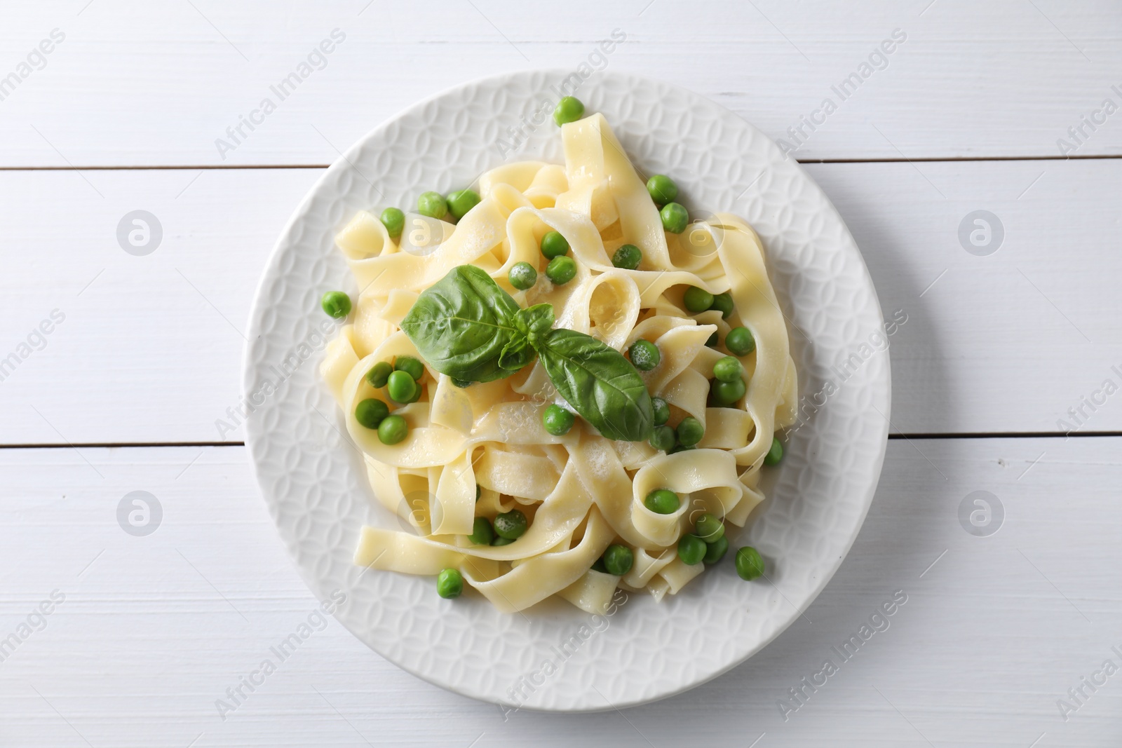 Photo of Delicious pasta with green peas on white wooden table, top view