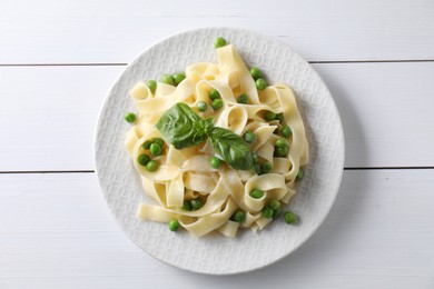 Photo of Delicious pasta with green peas on white wooden table, top view