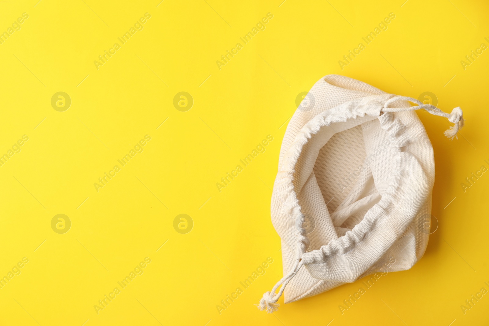 Photo of Cotton eco bag on yellow background, top view. Space for text