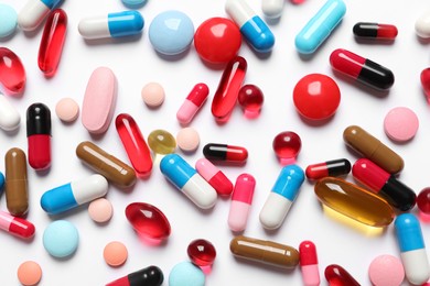 Photo of Lots of different colorful pills on white background, top view