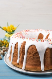 Photo of Glazed Easter cake with sprinkles on light blue wooden table, closeup