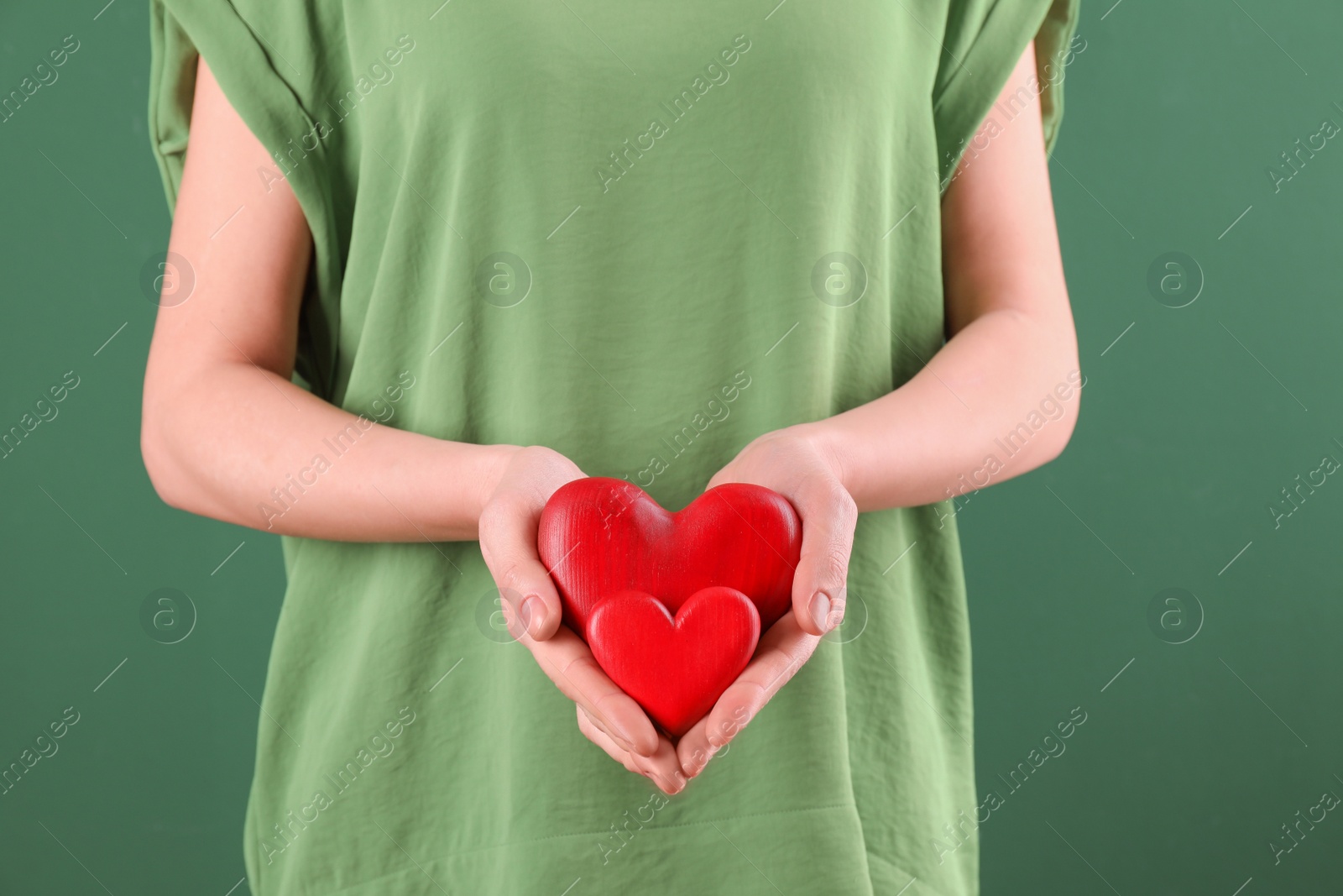 Photo of Woman holding decorative hearts on color background, closeup