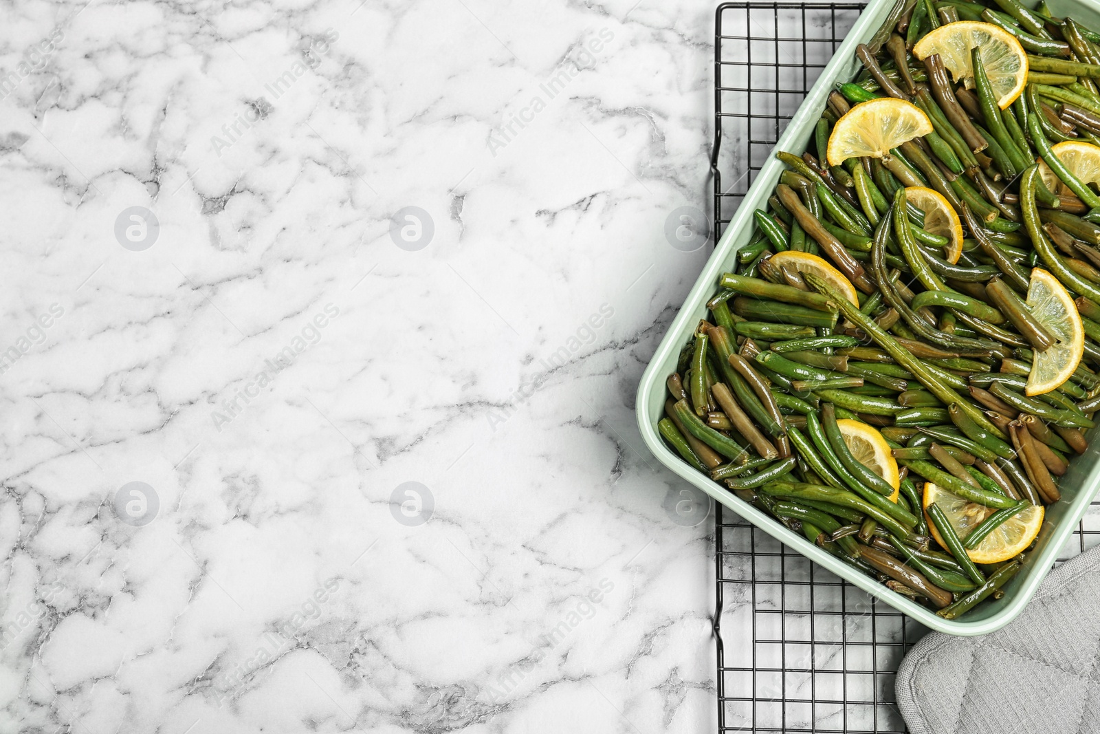 Photo of Dish with tasty green beans and lemons on marble table, top view