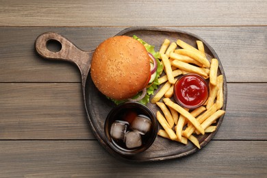 Photo of French fries, tasty burger, sauce and drink on wooden table, top view