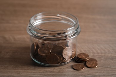 Glass jar with coins on wooden table