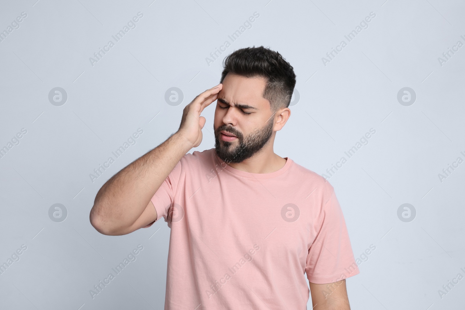 Photo of Young man suffering from headache on light background