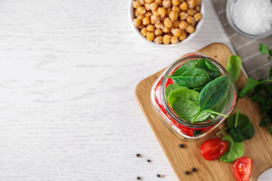 Photo of Healthy salad in glass jar on white table, flat lay. Space for text