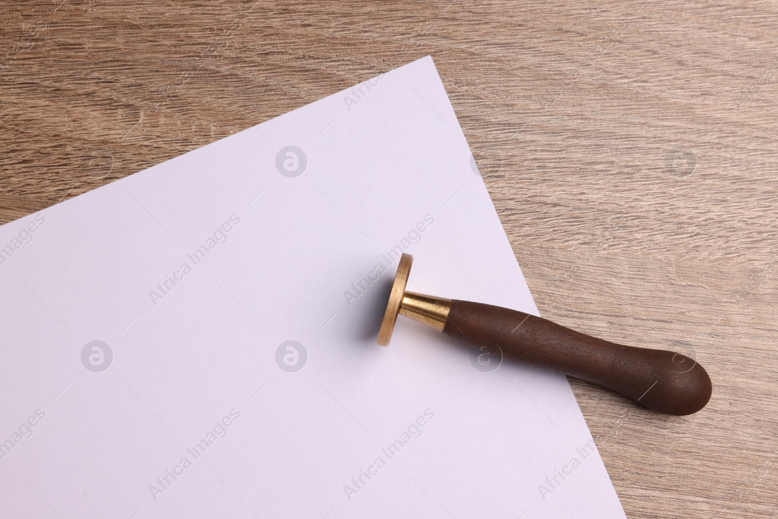 Photo of One stamp tool and sheet of paper on wooden table, top view. Space for text