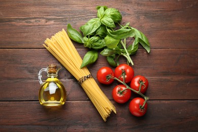 Photo of Raw pasta, spices and products on wooden table, flat lay