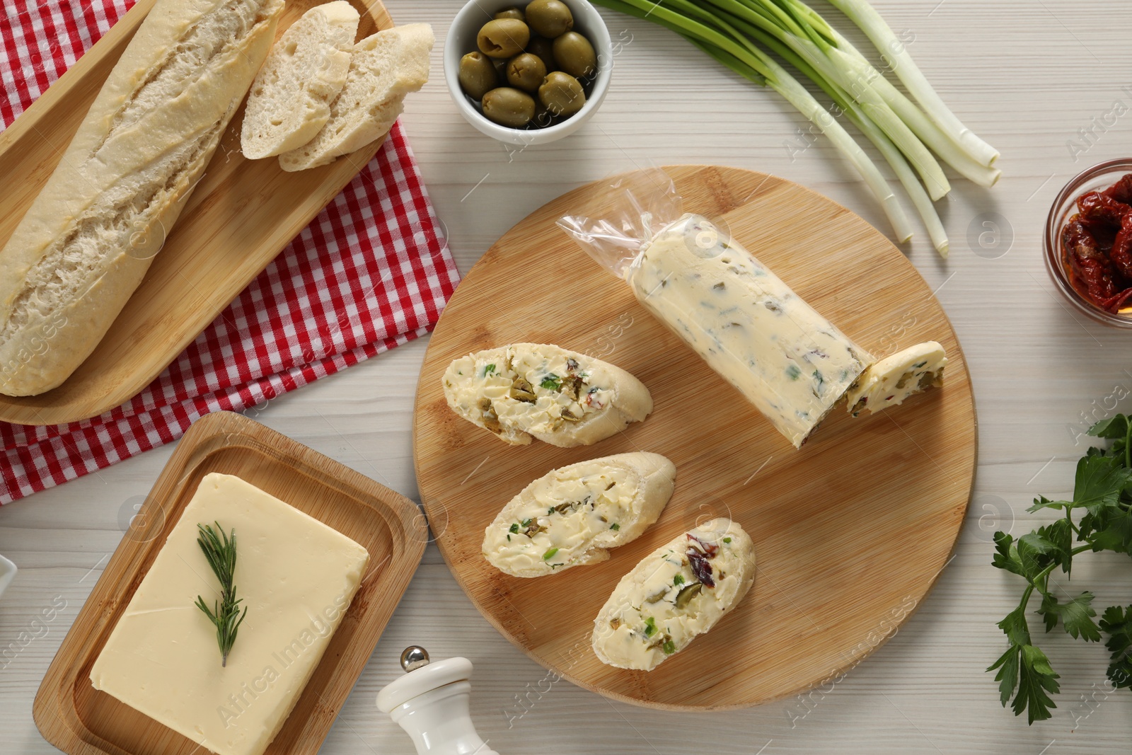 Photo of Tasty butter, bread and other ingredients on wooden table, flat lay