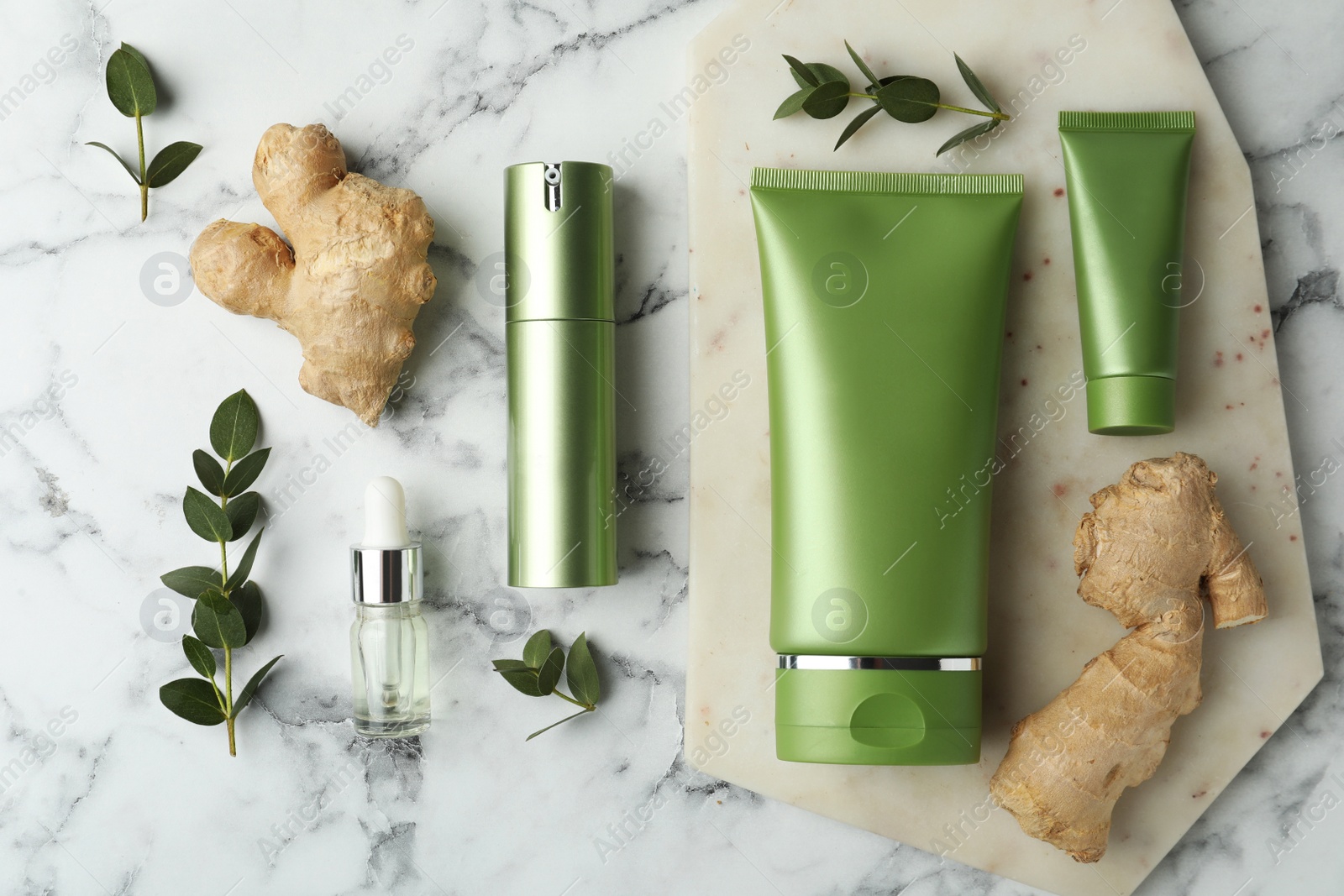 Photo of Set of cosmetic products, ginger and plants on white marble table, flat lay