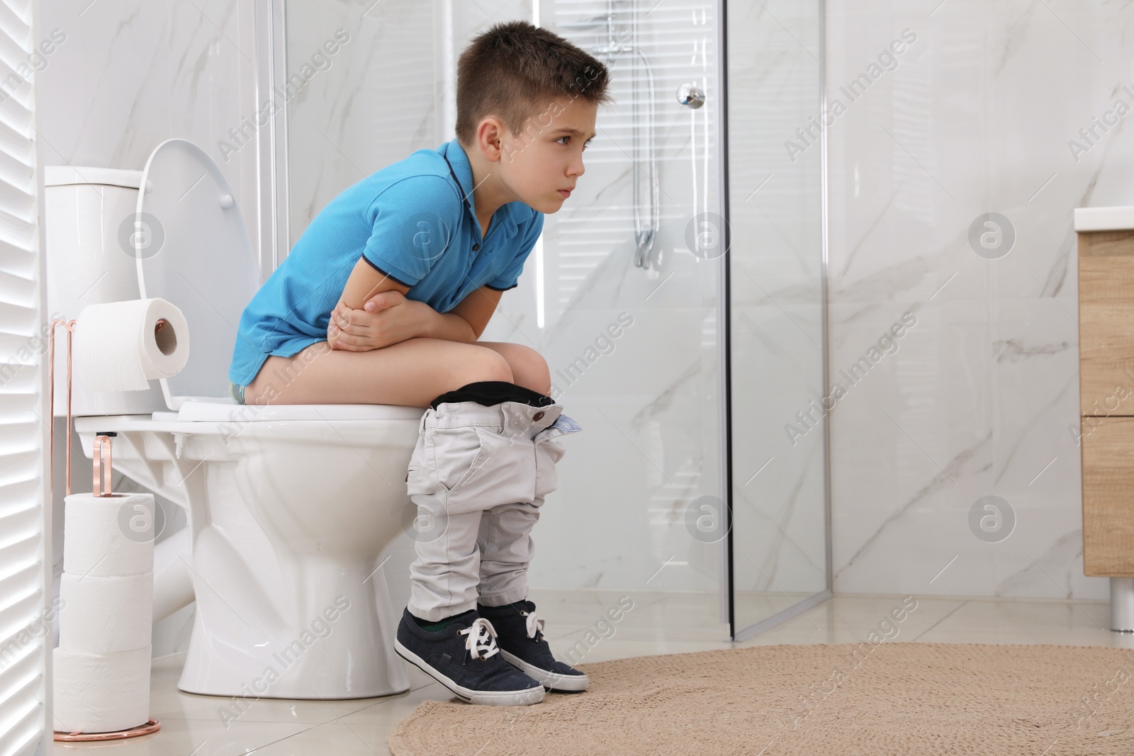 Photo of Boy suffering from hemorrhoid on toilet bowl in rest room