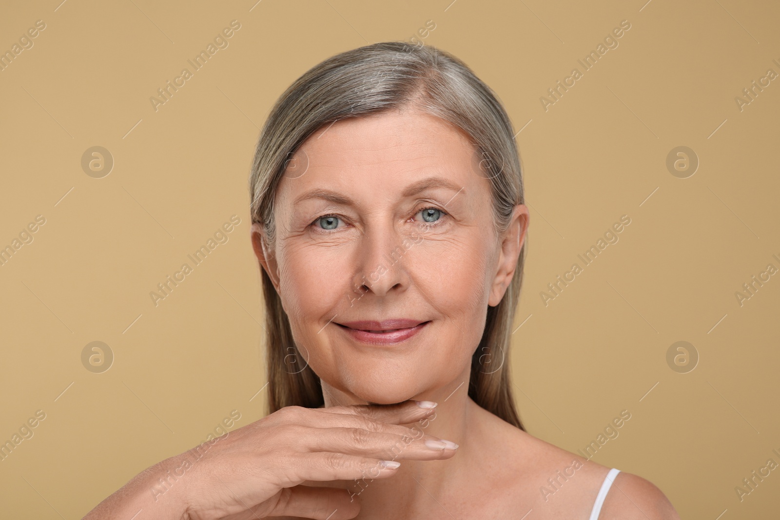 Photo of Portrait of senior woman with aging skin on beige background. Rejuvenation treatment