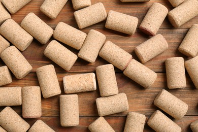 Many corks of wine bottles on wooden table, flat lay