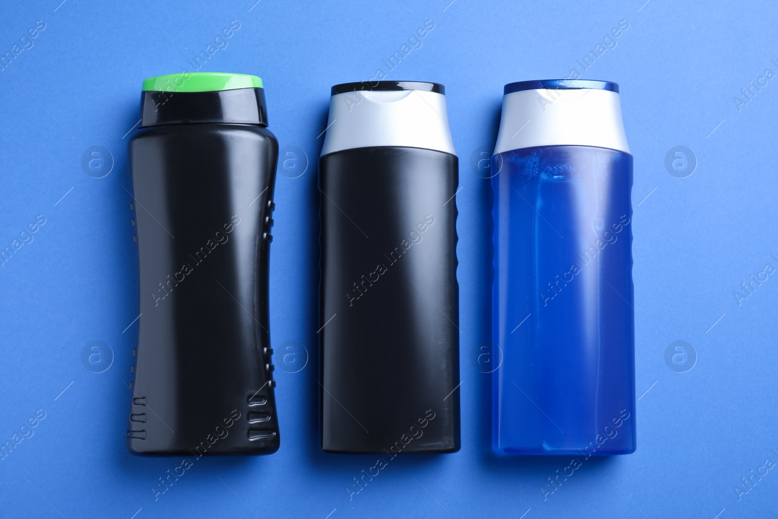 Photo of Different bottles on blue background, flat lay. Men's cosmetics