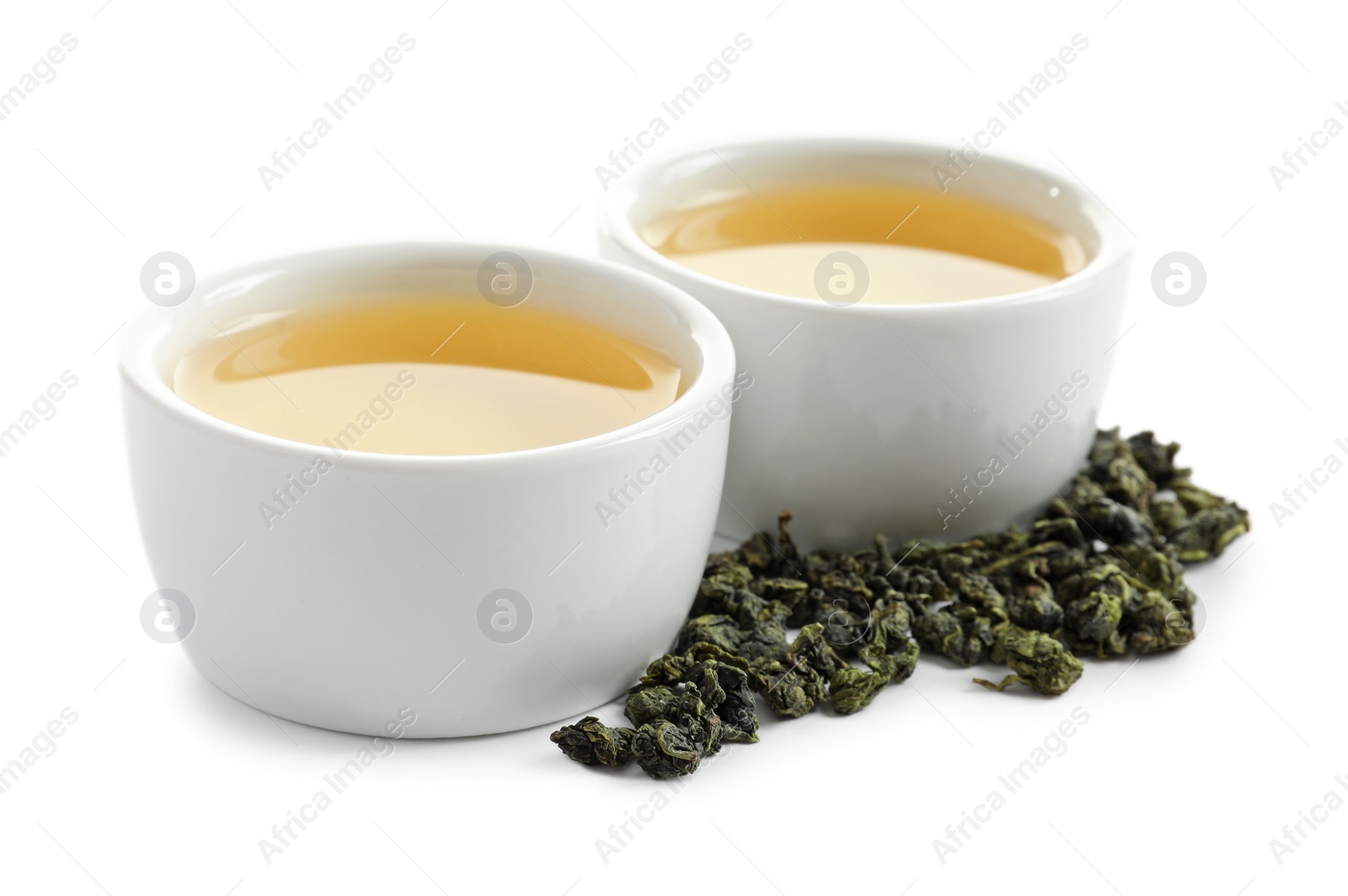 Photo of Cups of Tie Guan Yin oolong and tea leaves on white background