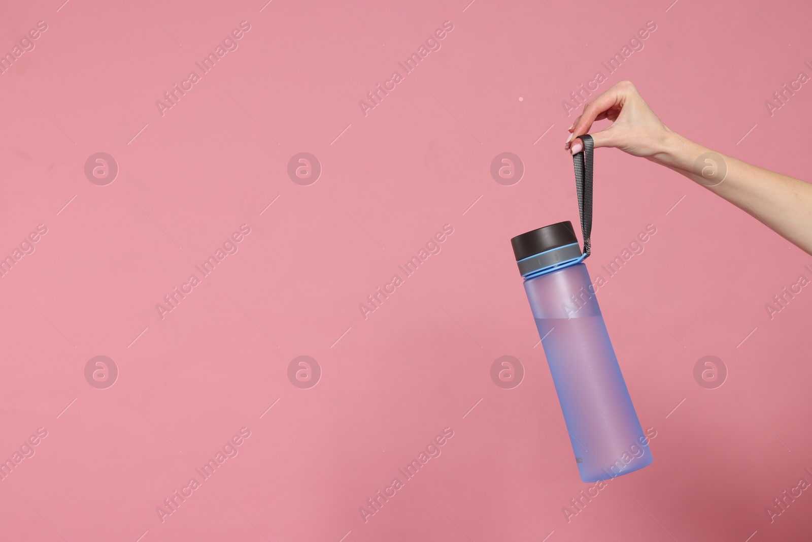 Photo of Woman holding transparent bottle on pink background, closeup. Space for text