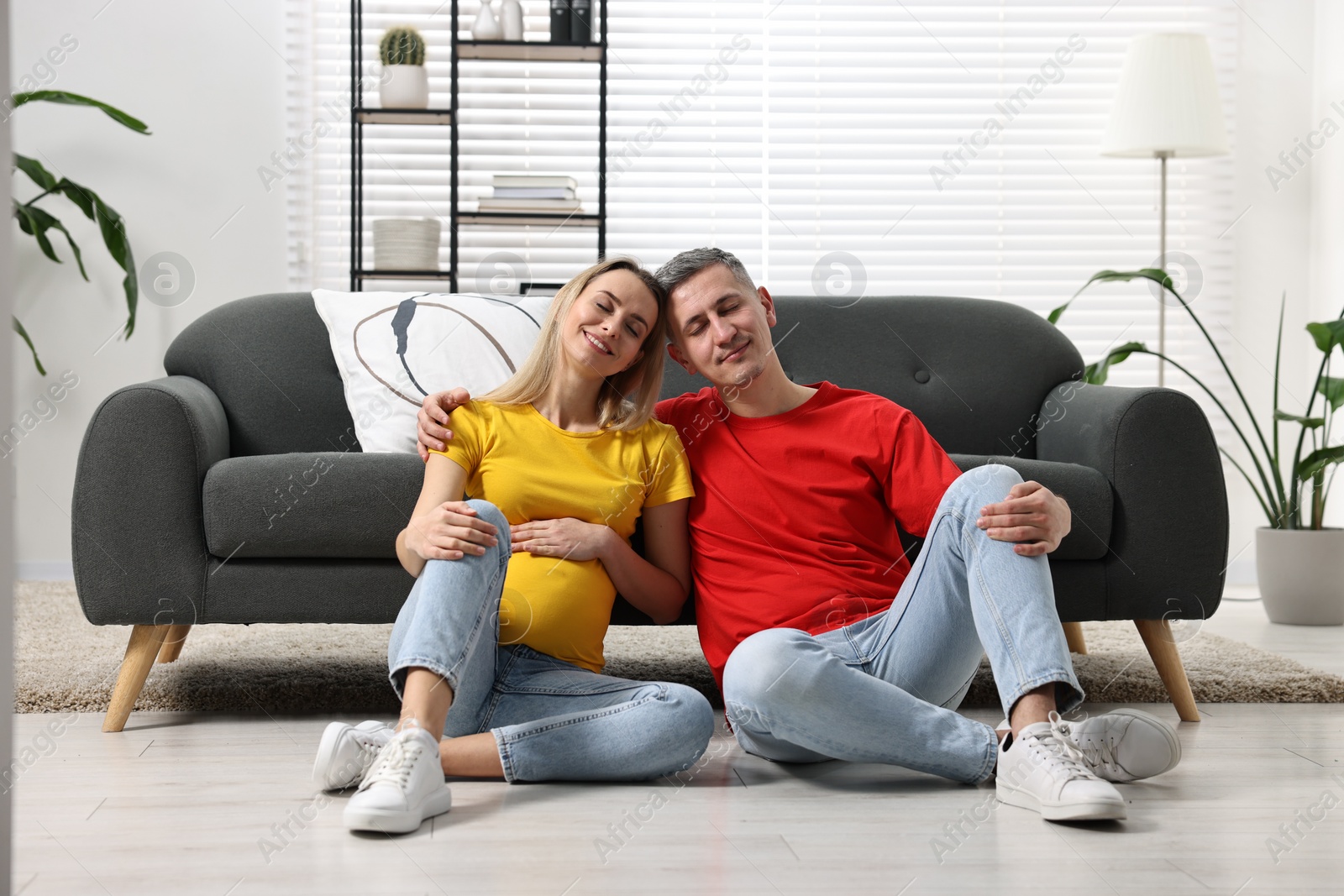 Photo of Young family housing concept. Pregnant woman with her husband on floor at home