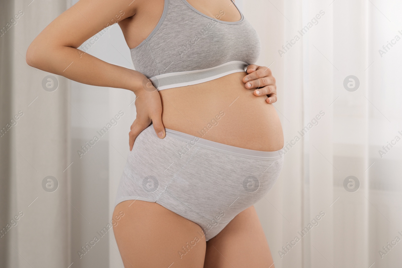 Photo of Pregnant woman in comfortable maternity underwear indoors, closeup