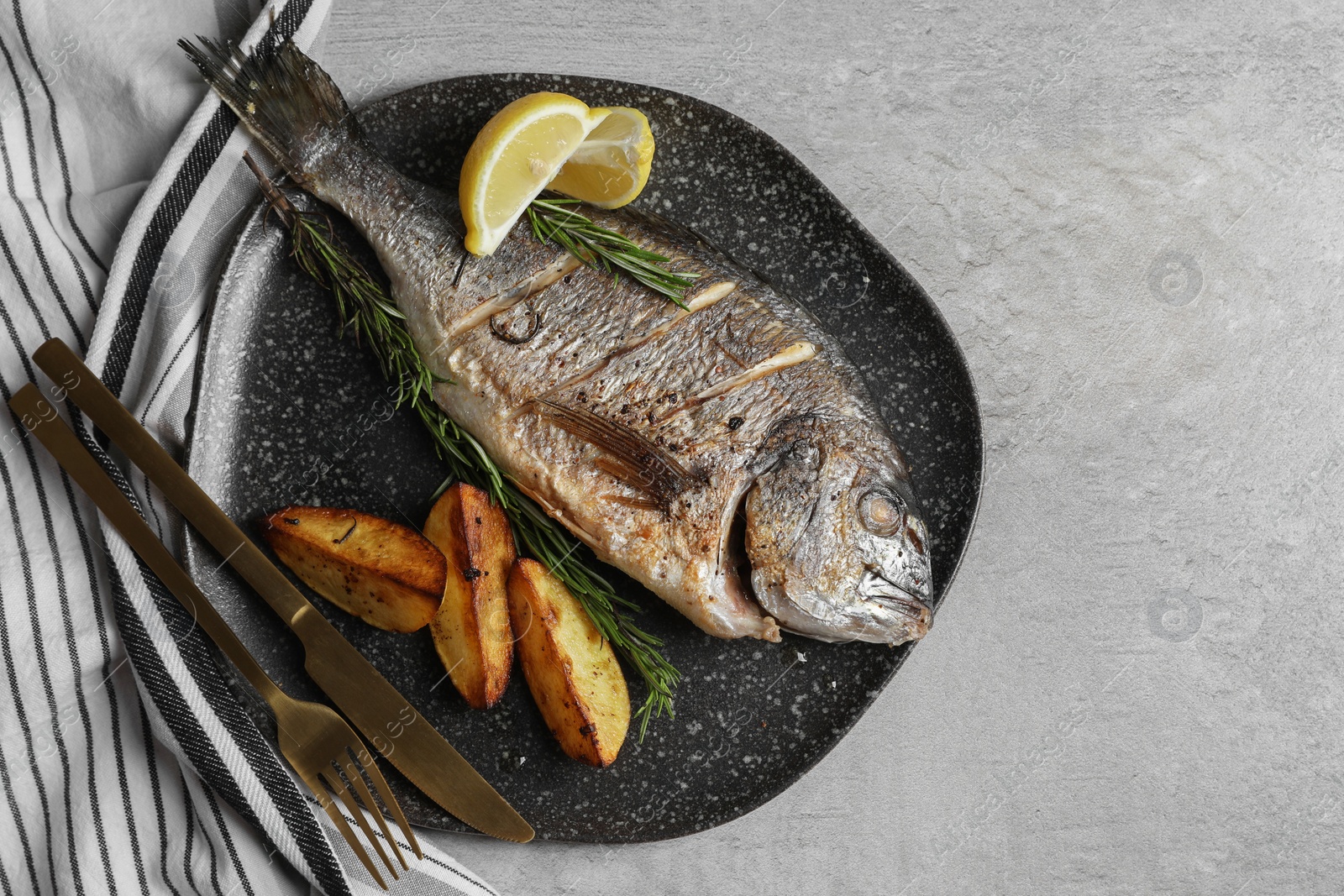 Photo of Seafood. Delicious baked fish served on grey table, top view with space for text