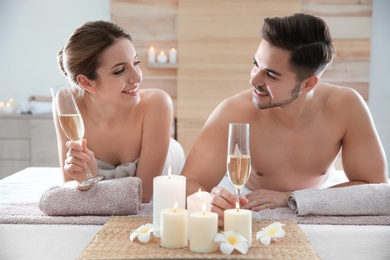 Photo of Romantic young couple with champagne in spa salon