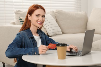 Happy woman with credit card using laptop for online shopping at home