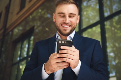 Photo of Young man using smartphone outdoors, focus on hands