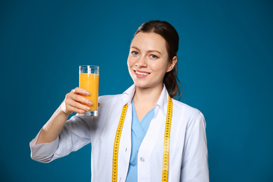 Photo of Nutritionist with glass of juice on blue background