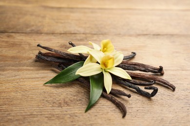 Beautiful vanilla flowers and sticks on wooden table, closeup