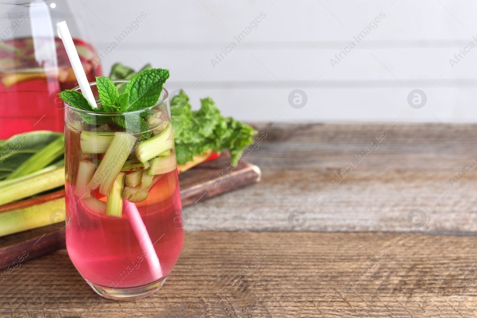 Photo of Glass of tasty rhubarb cocktail on wooden table, space for text
