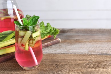 Glass of tasty rhubarb cocktail on wooden table, space for text