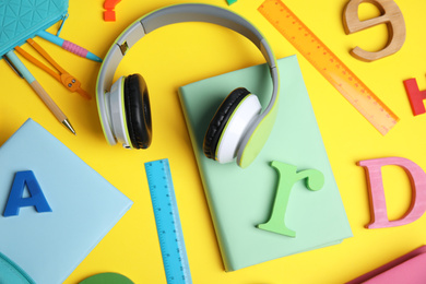 Flat lay composition with books and headphones on yellow background