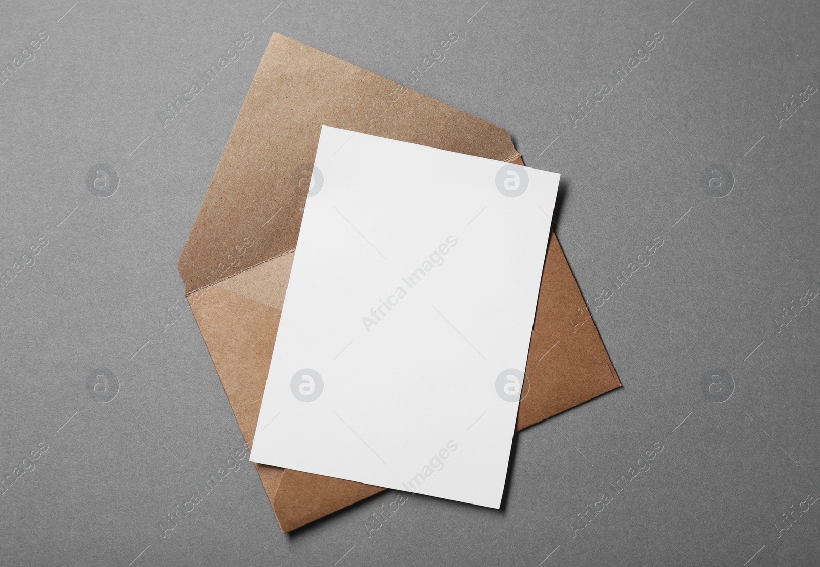 Photo of Blank sheet of paper and letter envelope on grey background, top view