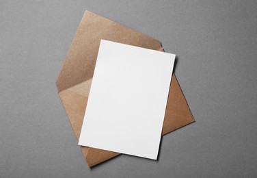 Photo of Blank sheet of paper and letter envelope on grey background, top view