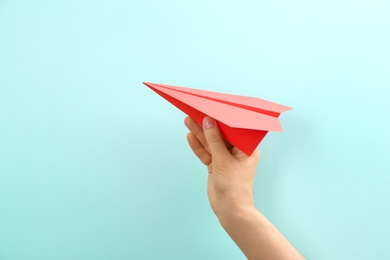 Photo of Woman holding paper plane on light blue background, closeup