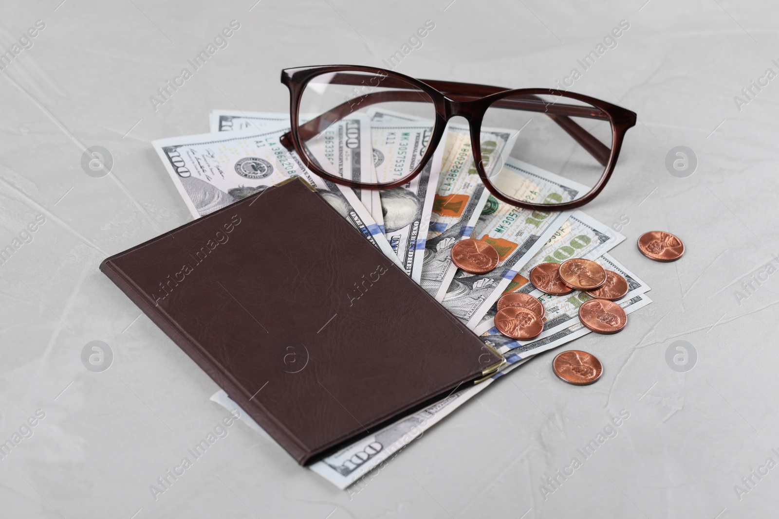 Photo of Pension certificate with American money and glasses on grey stone background