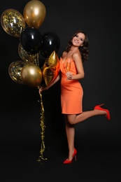 Photo of Happy woman with air balloons and glass of champagne on black background. Christmas party