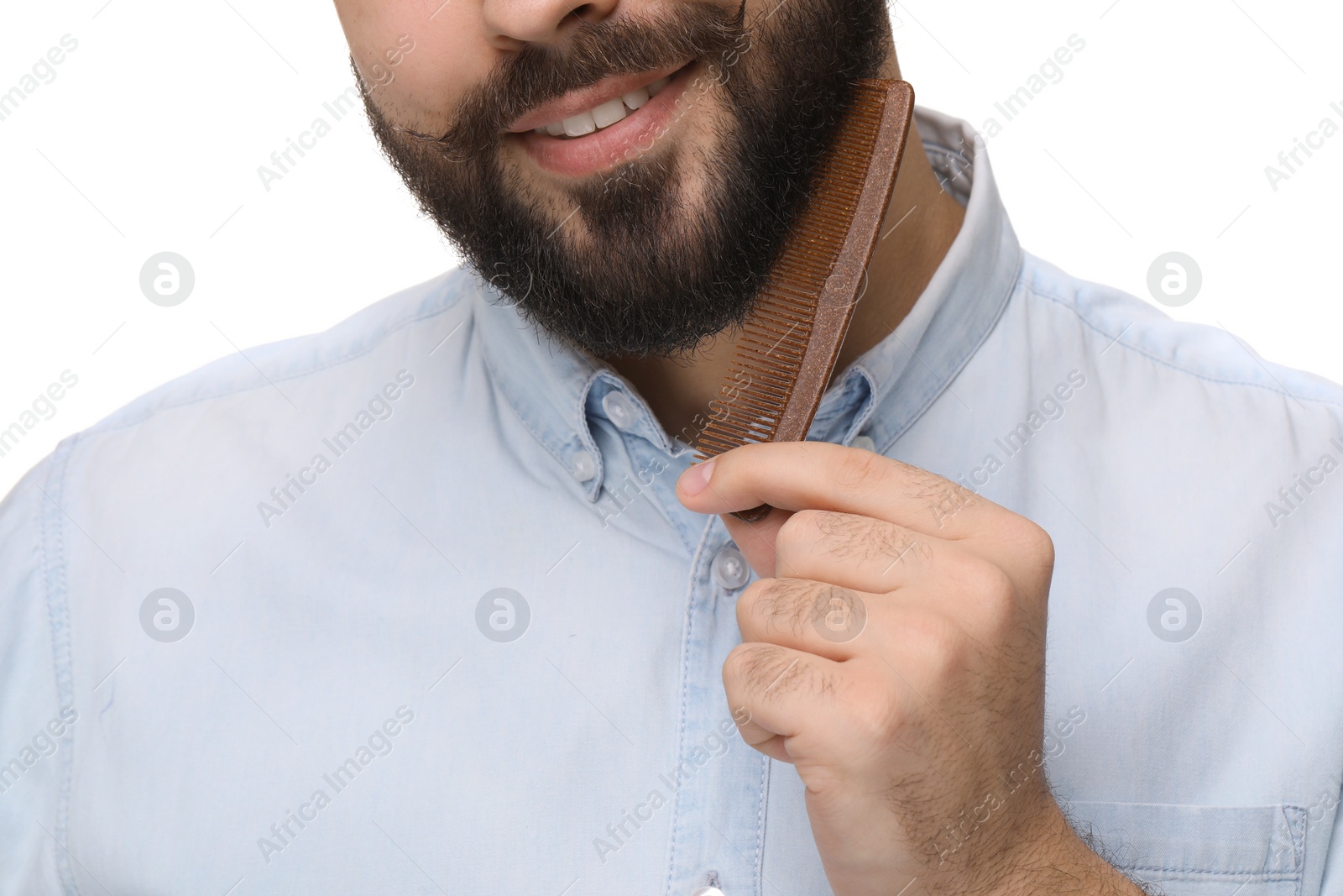 Photo of Handsome young man combing beard on white background, closeup