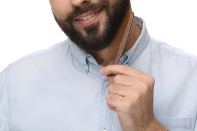 Photo of Handsome young man combing beard on white background, closeup