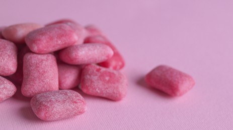 Photo of Heap of tasty sweet chewing gums on pink background, closeup