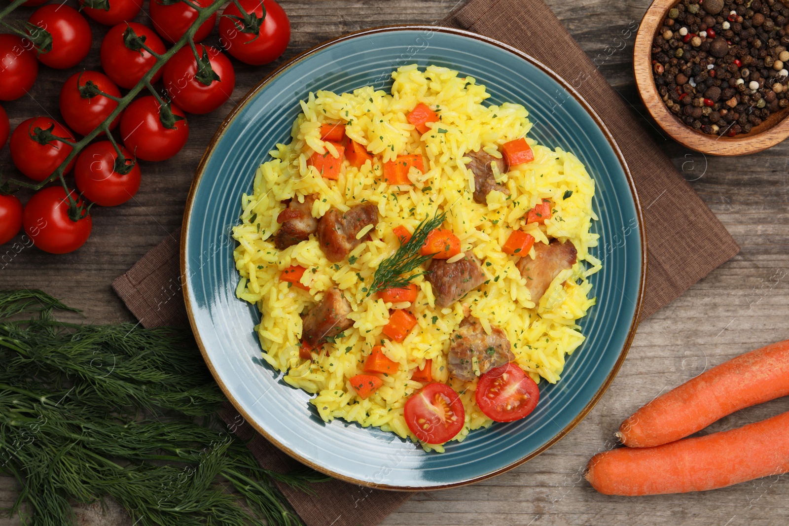 Photo of Delicious pilaf with meat and ingredients on wooden table, flat lay